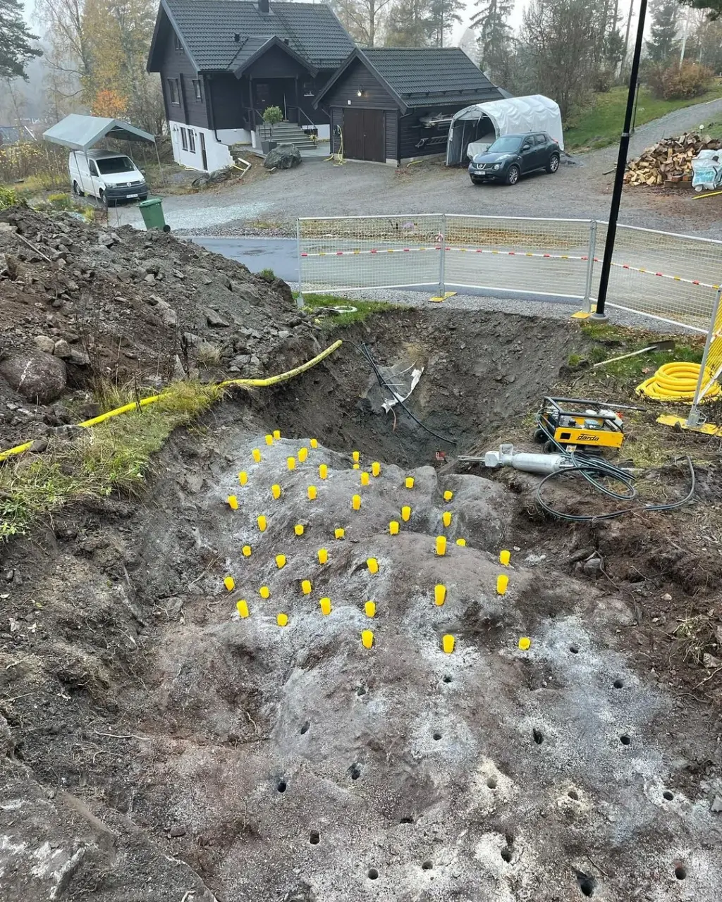 Borrade hål i berg markerade med gula pluggar inför sprängning